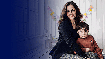 Mother and son sitting together, smiling indoors.